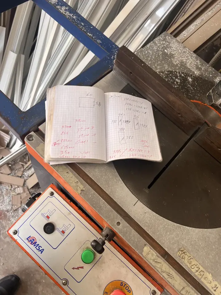 Carnet de calculs ouvert sur la scie d'un atelier d'aluminium
